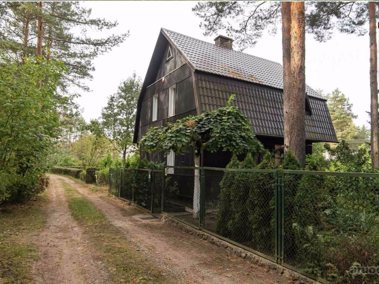 Traditional wooden house with sloped roof in a forested area of Vilnius region.